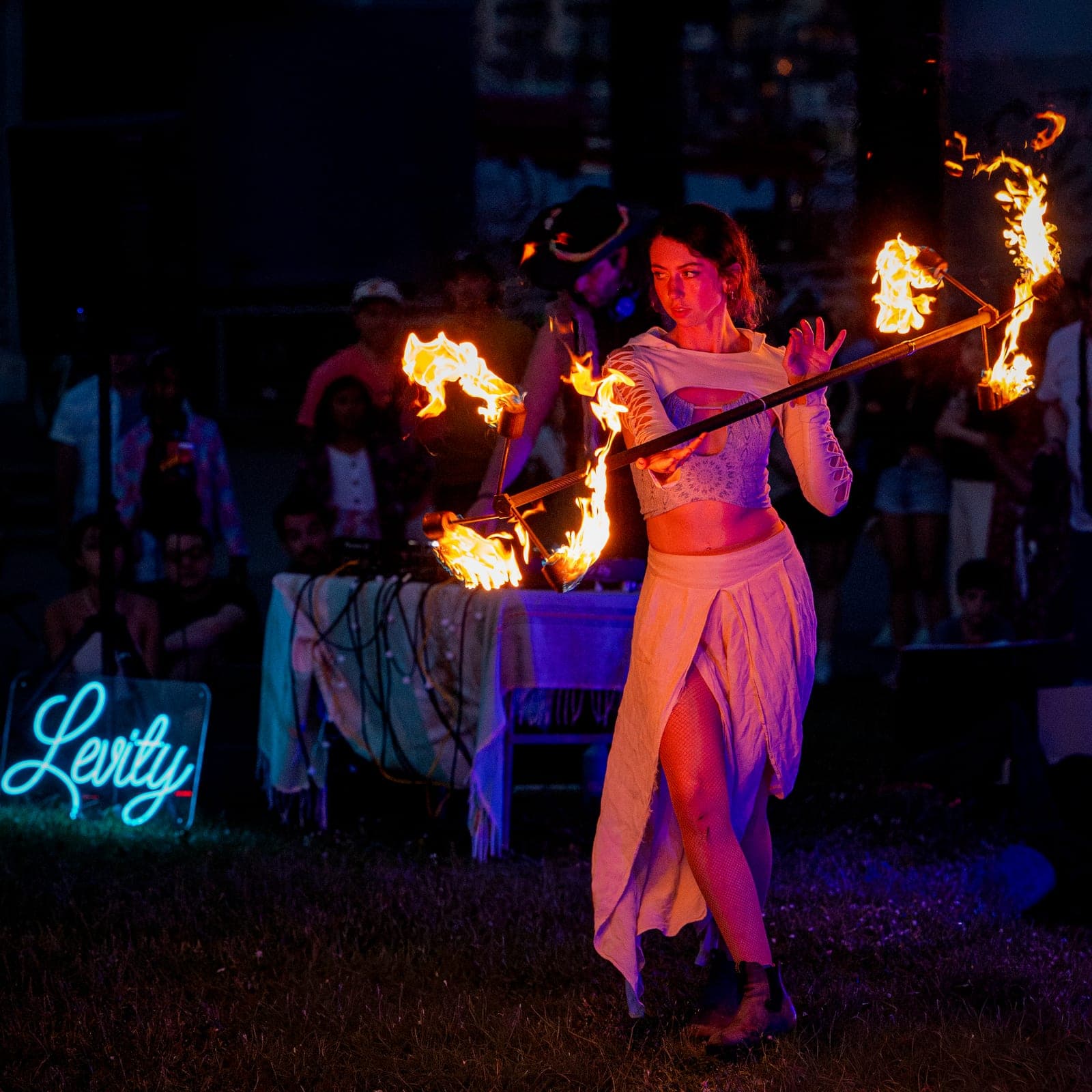 A fire performer spinning lit fans in front of a crowd