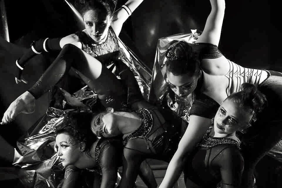A group of dancers posed together in a black-and-white studio portrait