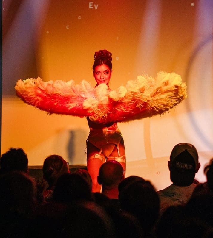 A classic burlesque performer behind a large feather fan