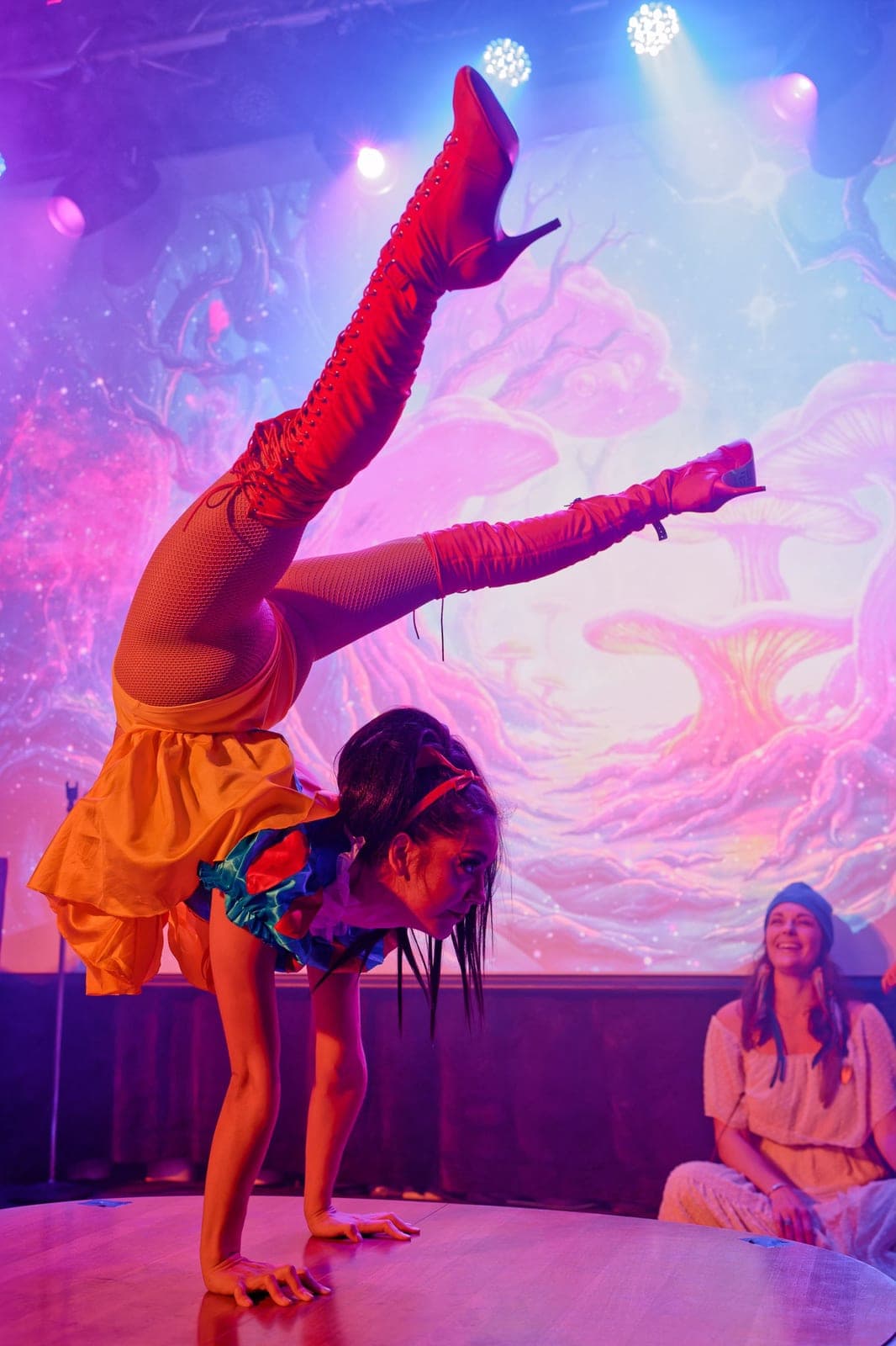 Josey mid-handstand in an orange skirt under purple stage light